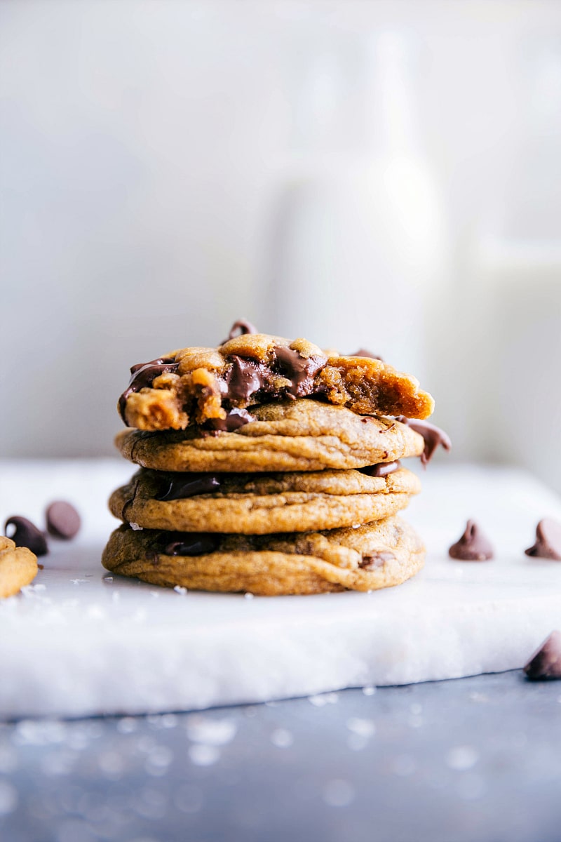 Image of Pumpkin Chocolate Chip Cookies stacked on top of each other with the top one with a bite out of it.